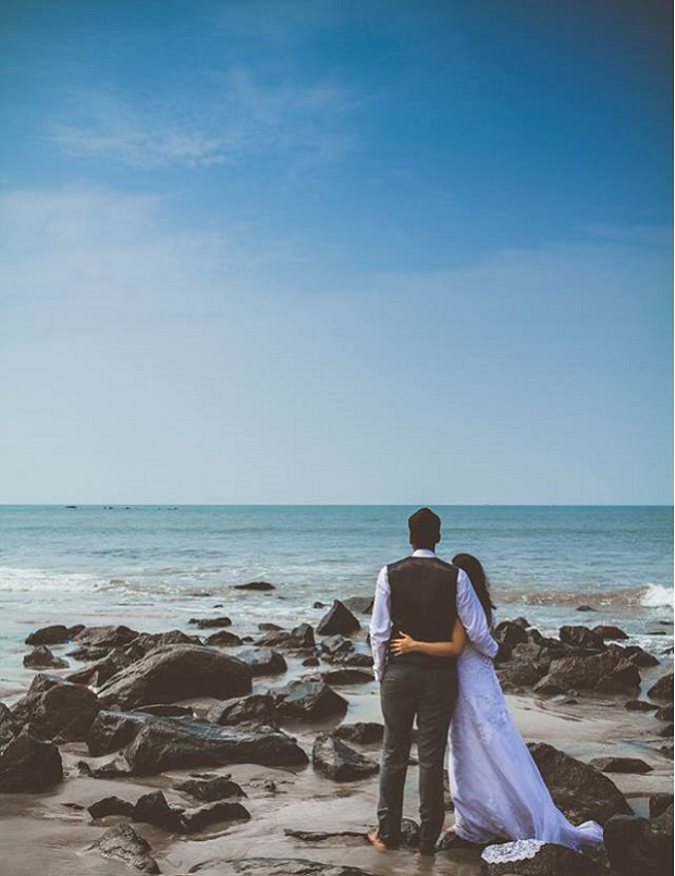 Indian Christian couple looking to the future on the beach after a fabulous wedding in Blue and green theme