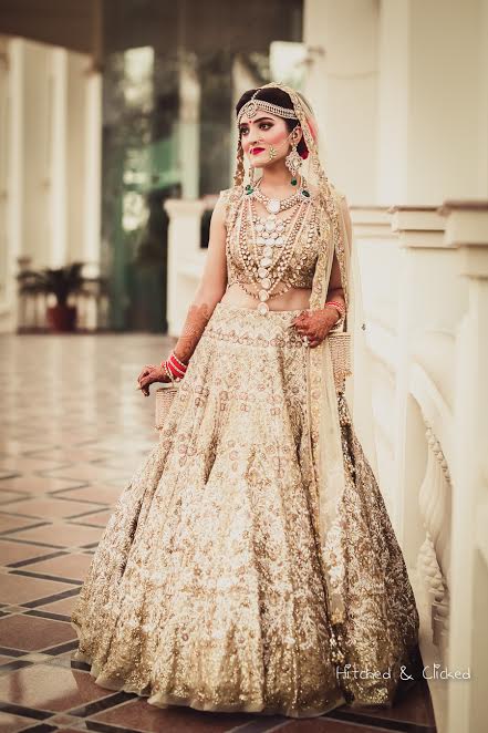 bride poses in a beautiful Golden beige lehenga by Harpreet and Rimple Narula