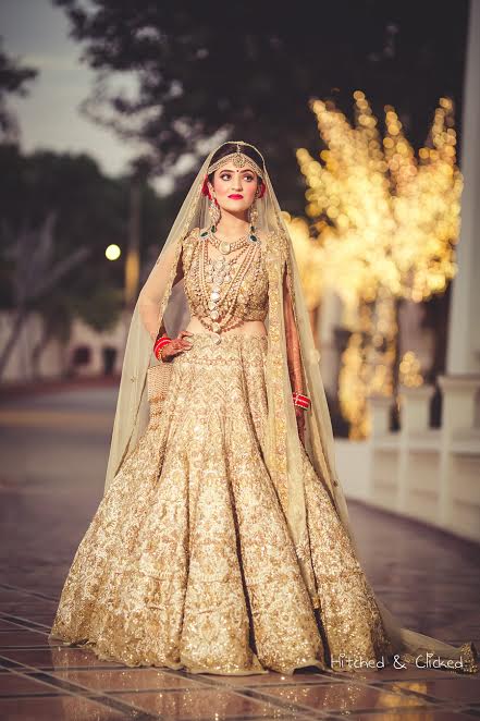 bride poses in a beautiful Golden beige lehenga by Harpreet and Rimple Narula